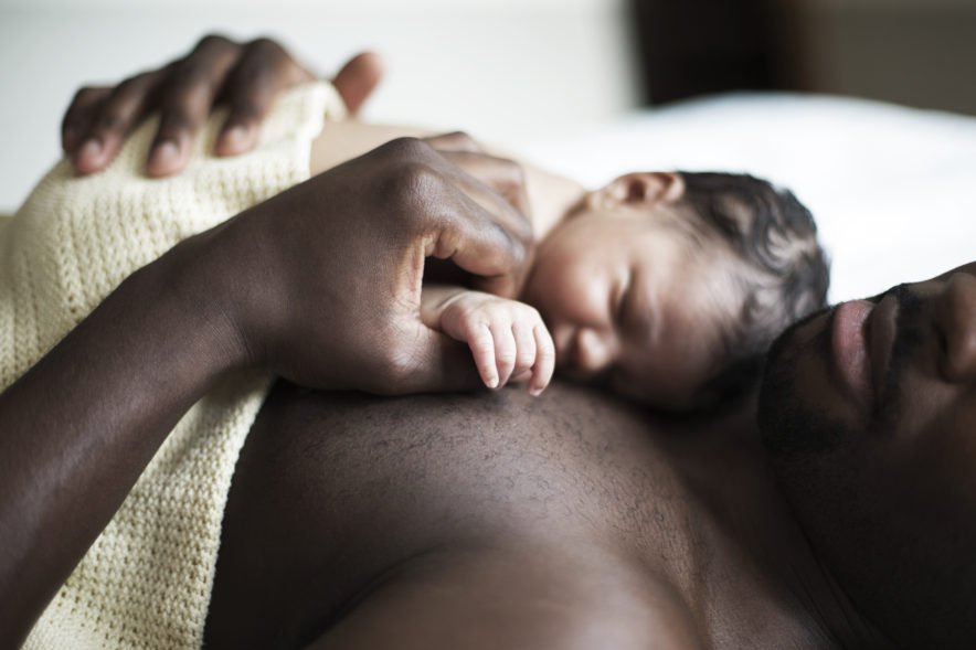 Baby laying on father's chest for skin-to-skin contact