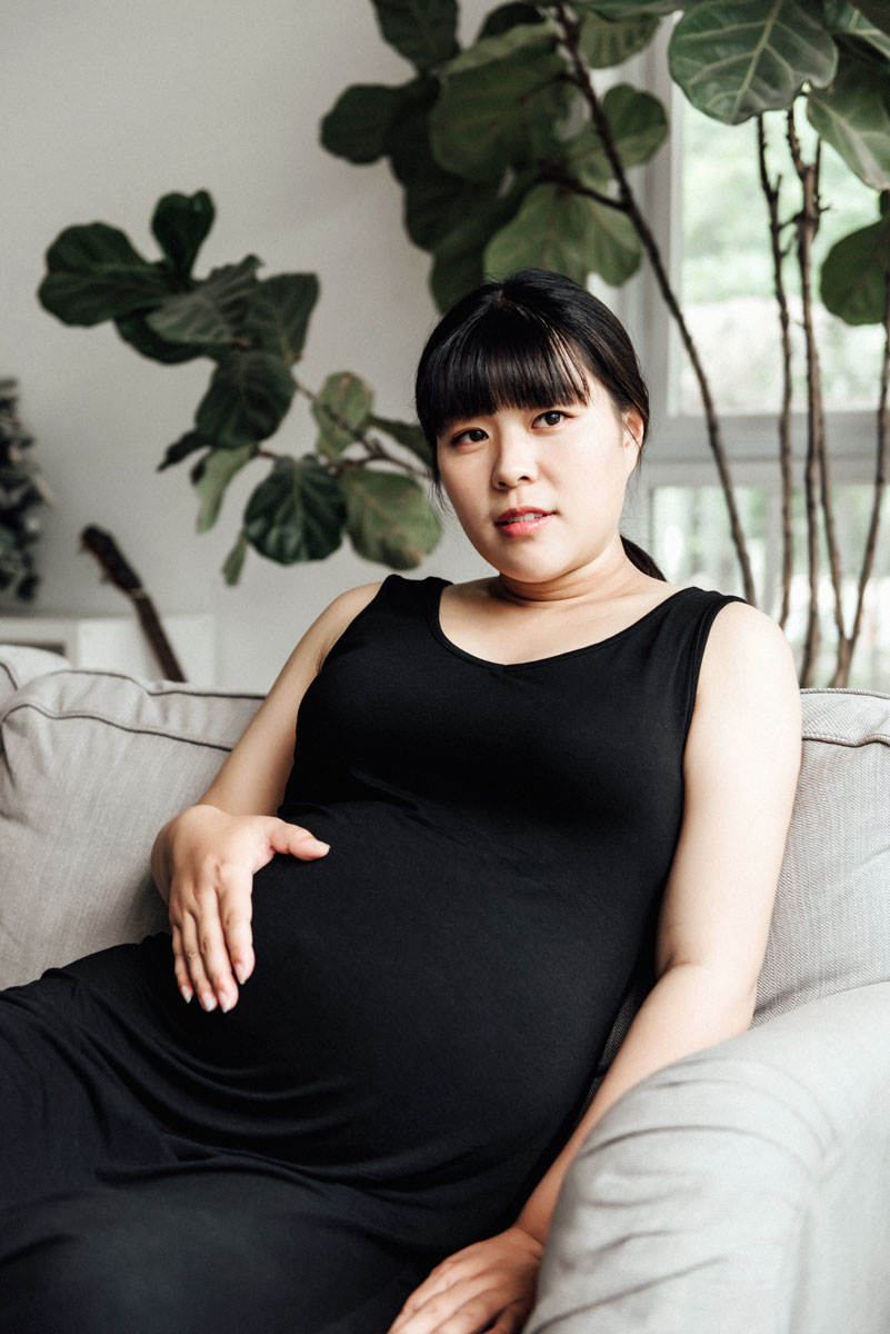 Concerned pregnant woman sitting on a couch with her hand on her belly